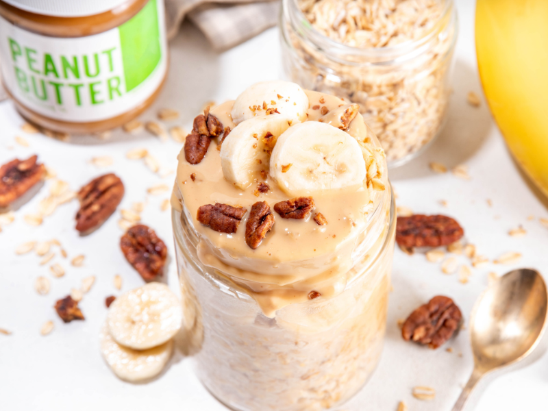 Healthy overnight oats with peanut butter and sliced banana in a glass jar
