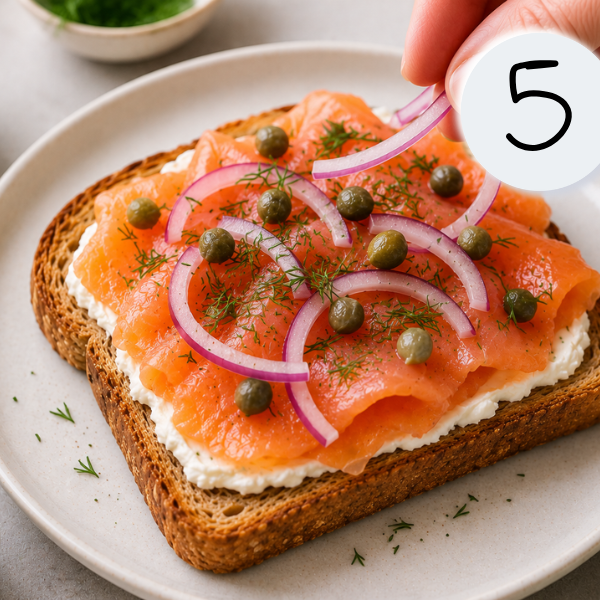 Thin slices of smoked salmon layered neatly over cream cheese on whole wheat toast.
