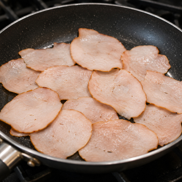 Lean turkey slices warming in a skillet before being added to a healthy breakfast wrap. 